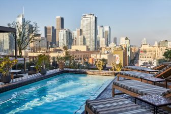 Rooftop Pool Deck with lounge chairs and view of downtown los angeles city skyline