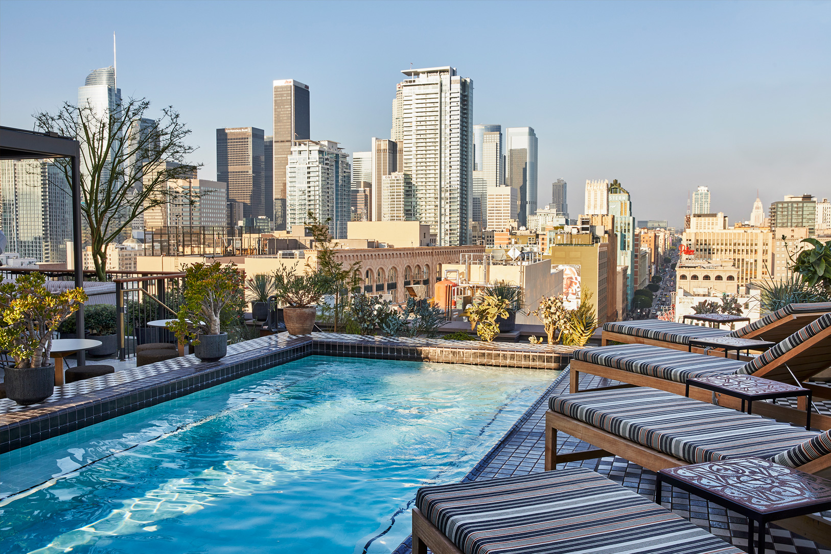 Rooftop Pool Deck with lounge chairs and view of downtown los angeles city skyline