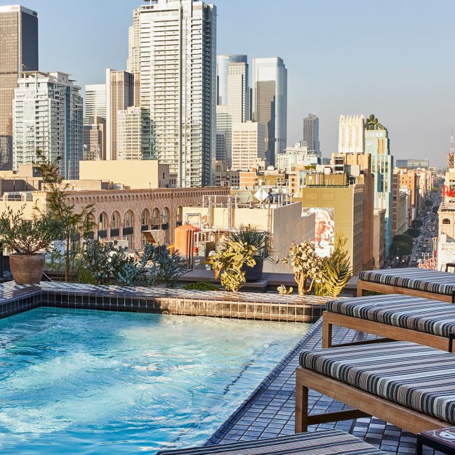 Rooftop Pool Deck with lounge chairs and view of downtown los angeles city skyline