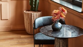 Modern seating nook with marble table, textured chair, floral arrangement, and warm interior accents