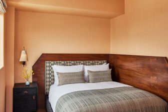 Downtown LA Proper Minimalist guestroom with warm wood accents and custom upholstered headboard