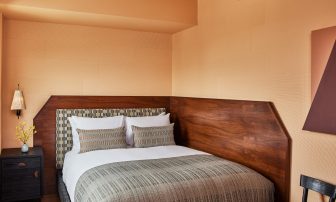 Contemporary guest room with custom wood headboard, plush king bed, and warm neutral interiors