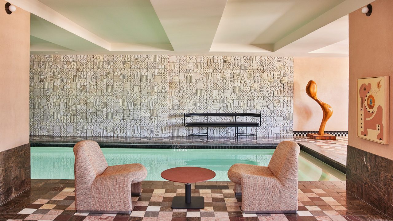 Indoor pool lounge with sculptural decor, patterned tile walls, and modern seating