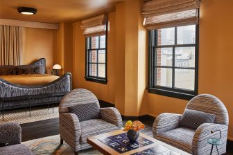 Luxury suite with lounge seating, oversized windows, and warm residential style interiors