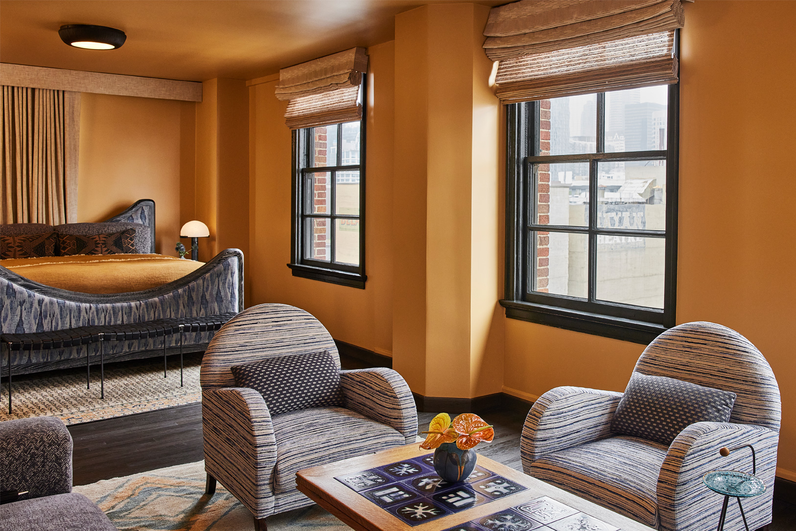 Luxury suite with lounge seating, oversized windows, and warm residential style interiors