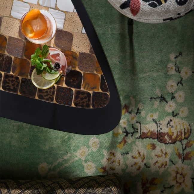 Cocktails served on a patterned table with mosaic surface and surrounding lounge seating