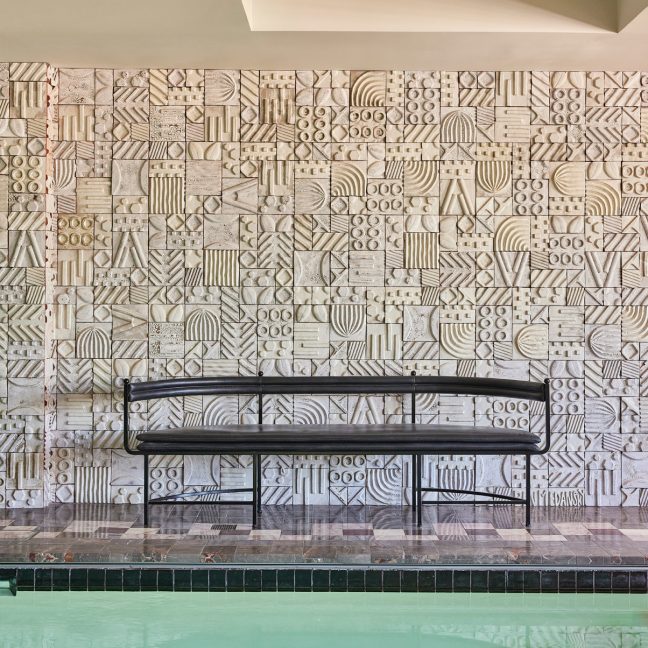 Indoor pool lounge with two chairs and a table facing a tiled wall