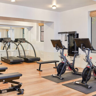 Bright fitness center with treadmills, spin bikes, strength equipment, and free weights