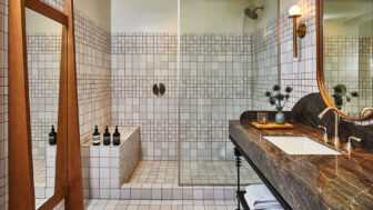 Modern tiled bathroom with walk in shower, marble vanity, and brass fixtures
