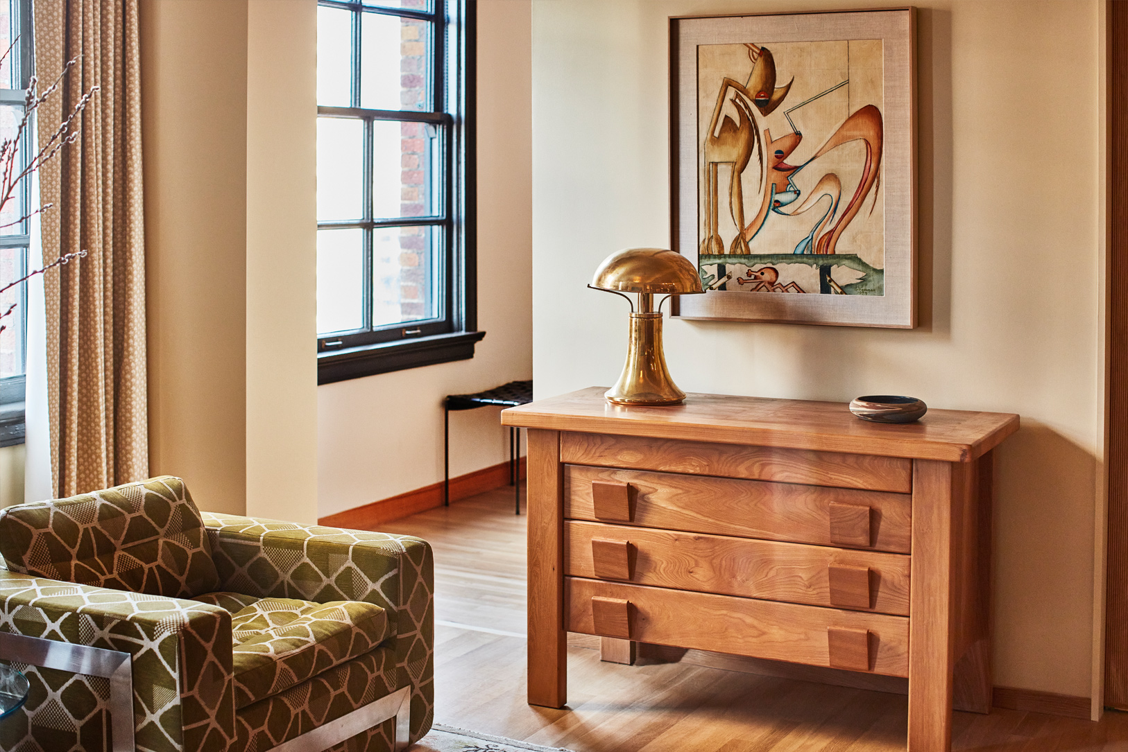 Elegant suite living area with custom artwork and warm wood furnishings