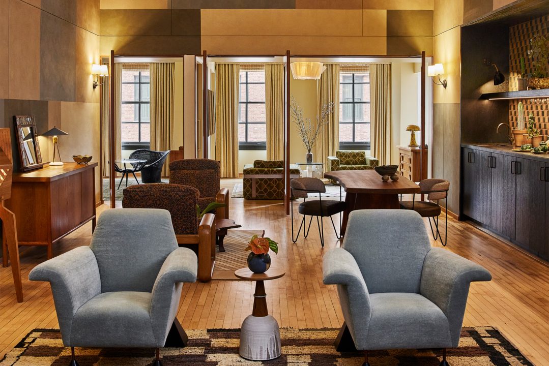 Spacious suite living area with modern furnishings, dining space, and warm Downtown LA inspired interiors
