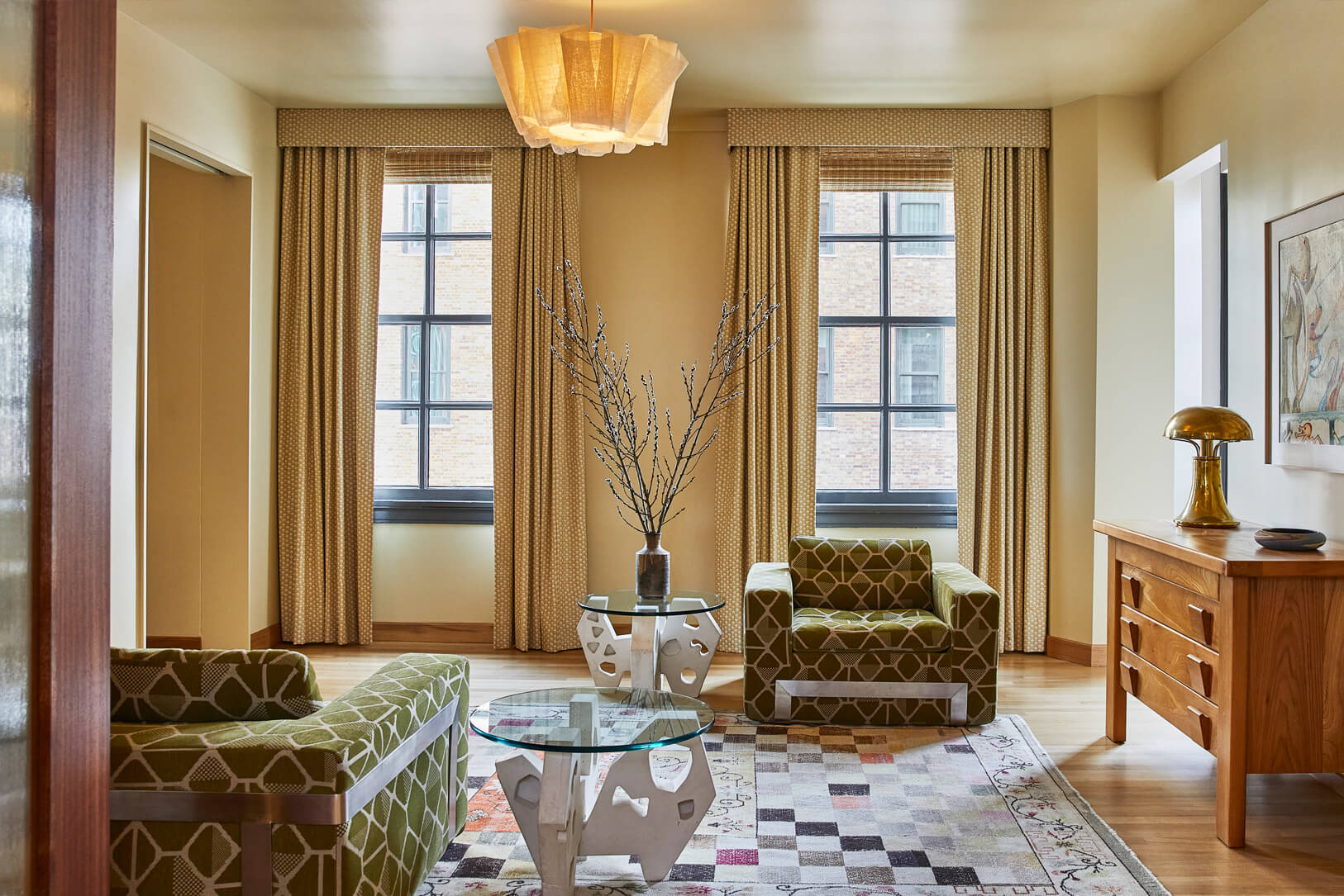 Elegant suite sitting area with floor to ceiling windows, custom furnishings, and natural light in Downtown LA