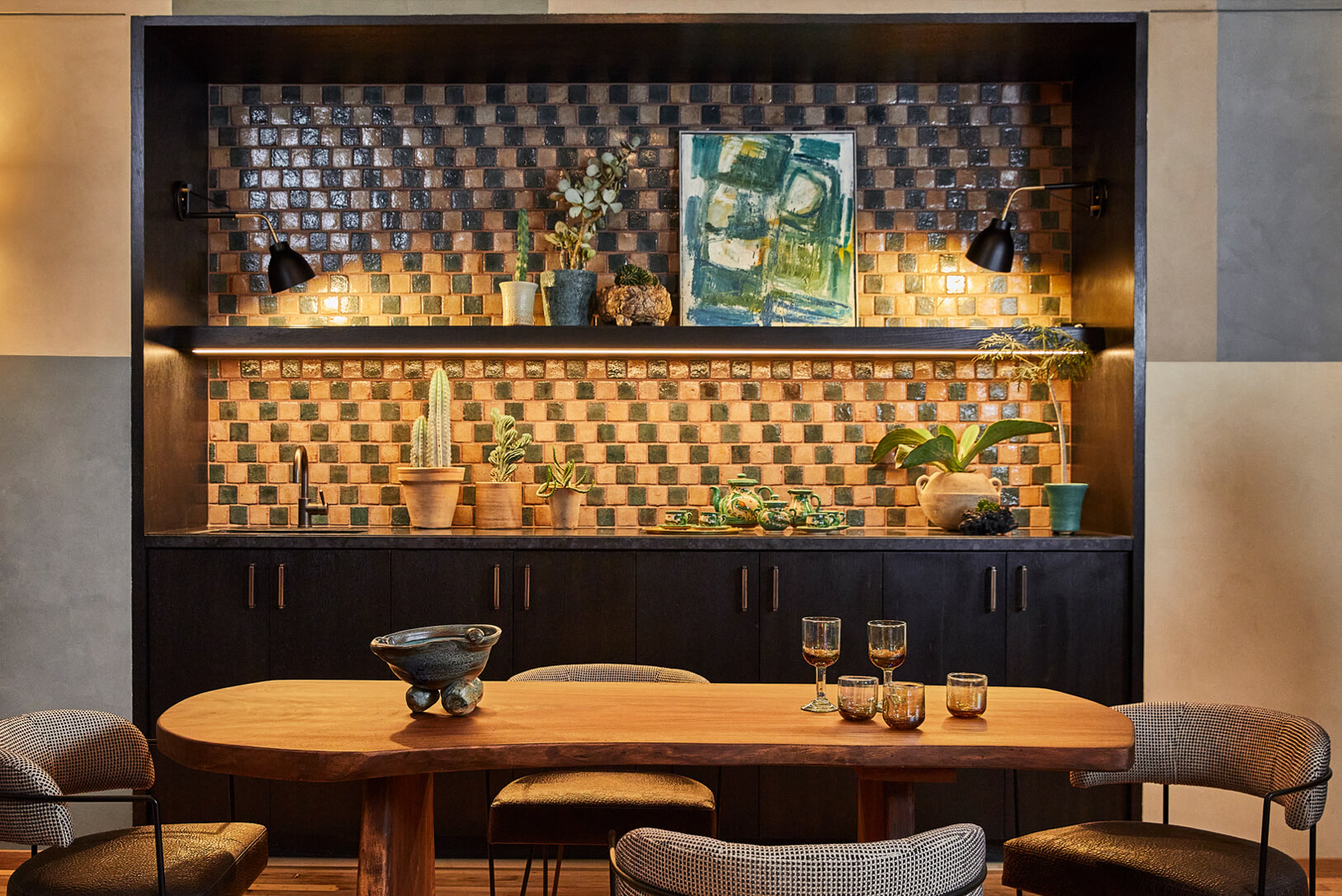 Stylish suite dining area with custom wood table, artisan tile kitchenette, and warm ambient lighting