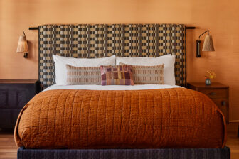 Warm contemporary bedroom with patterned headboard, layered pillows, and rich textured bedding