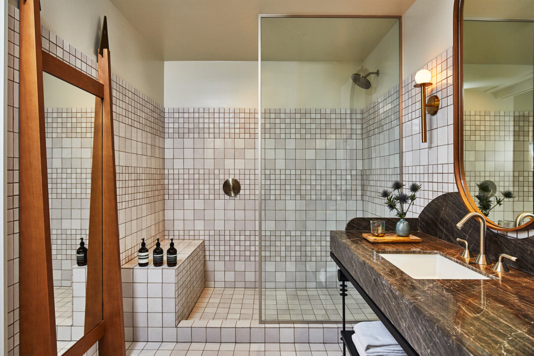 Downtown LA Proper bathroom with tiled walk in shower, marble vanity, and brass accents