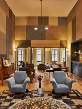 Spacious suite living area with modern furnishings, dining space, and warm Downtown LA inspired interiors