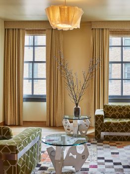 Elegant suite sitting area with floor to ceiling windows, custom furnishings, and natural light in Downtown LA