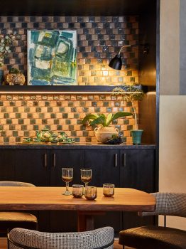 Stylish suite dining area with custom wood table, artisan tile kitchenette, and warm ambient lighting