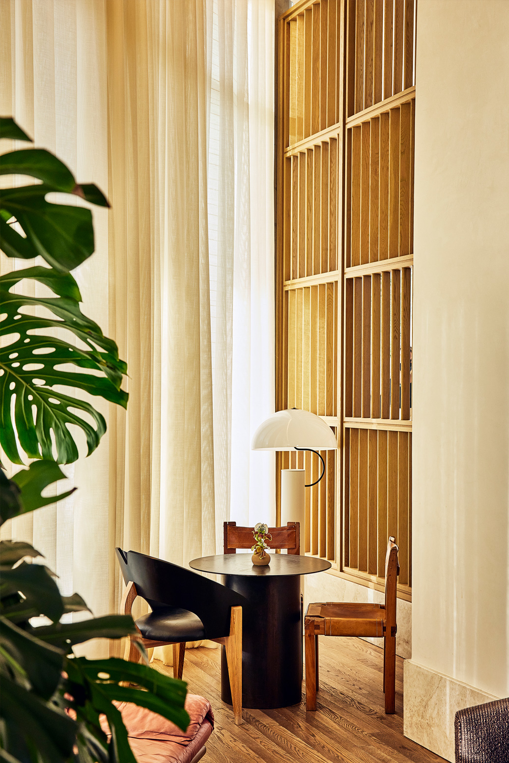 Intimate seating corner with modern wood accents, soft lighting, and floor to ceiling drapery