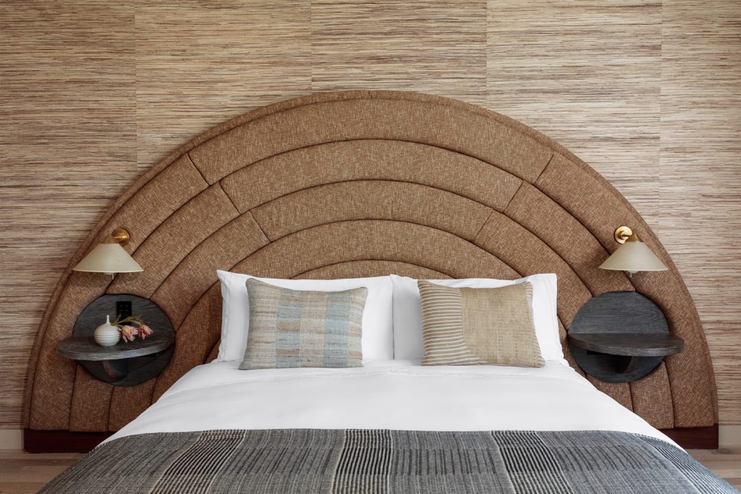 Luxury guest bed with curved upholstered headboard and modern bedside lighting