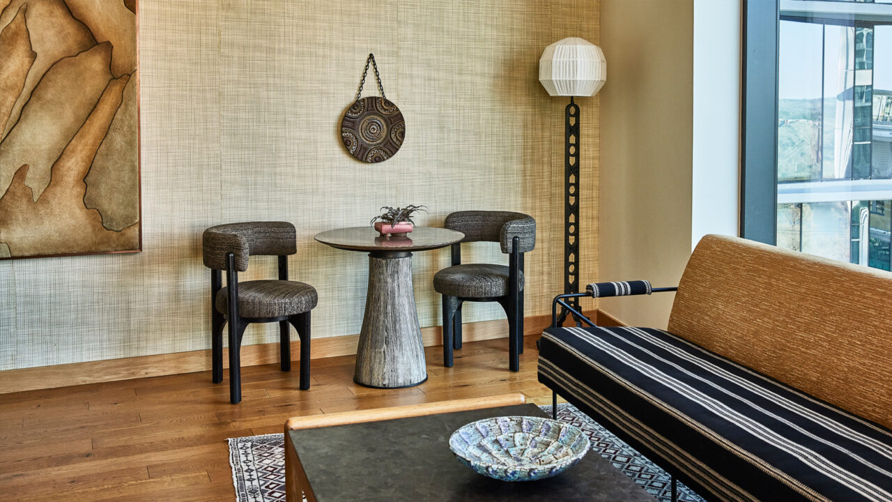 Corner seating area with armchair, side table, and floor-to-ceiling city view windows