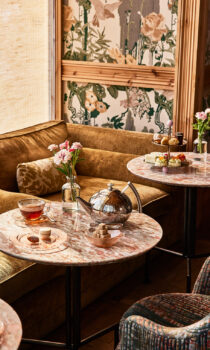 Cozy lounge seating with marble tables set for Goldies afternoon tea, featuring teapot, pastries, and soft natural light