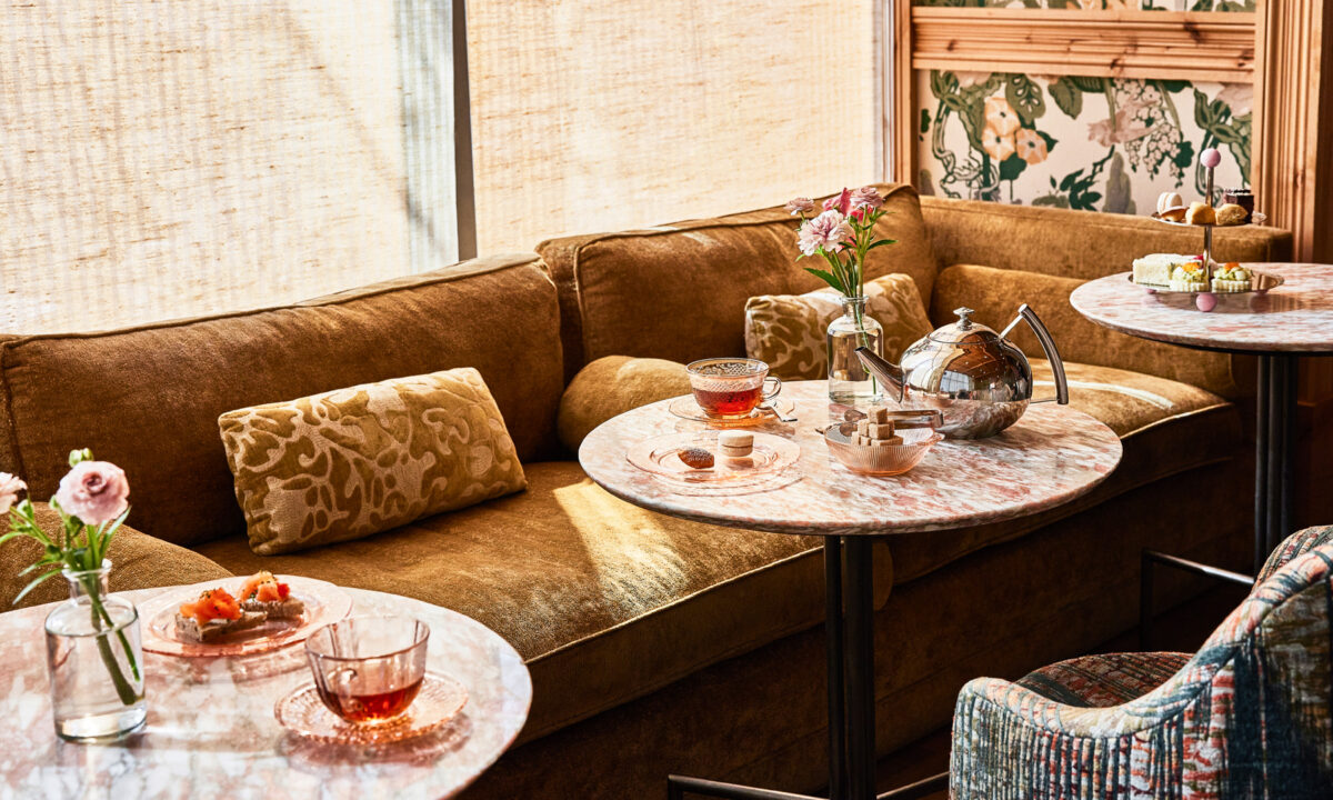 Cozy lounge seating with marble tables set for Goldies afternoon tea, featuring teapot, pastries, and soft natural light