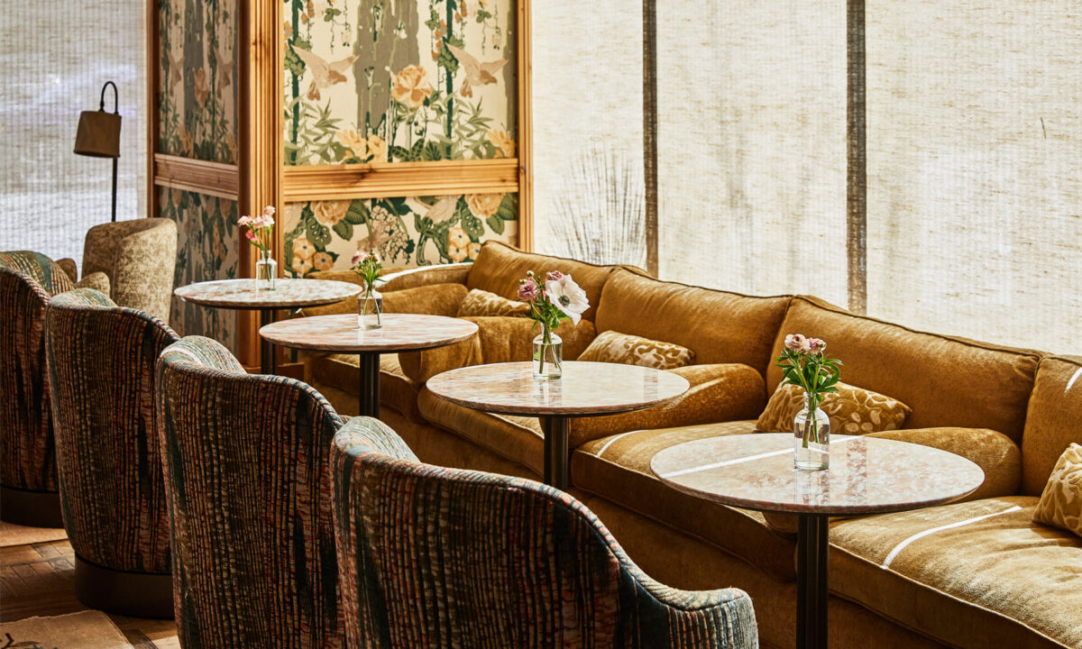 Cozy lounge with upholstered seating, marble tables, and small floral arrangements in soft natural light