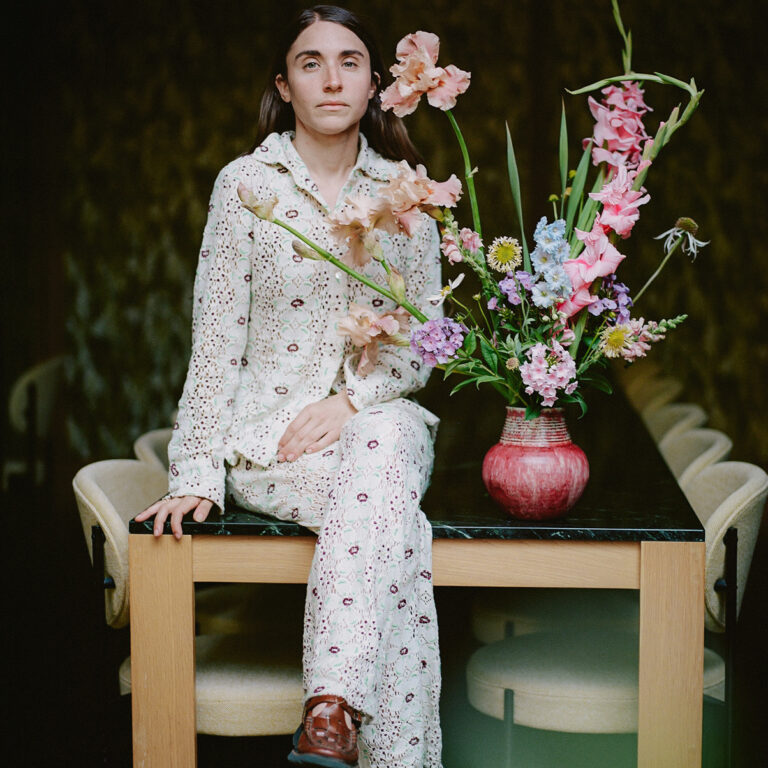 Person sitting at a table beside a vase of colorful flowers