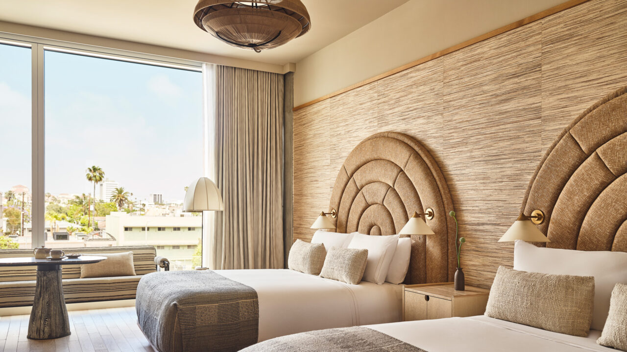 Luxury double guest room with curved upholstered headboards and large city-view windows