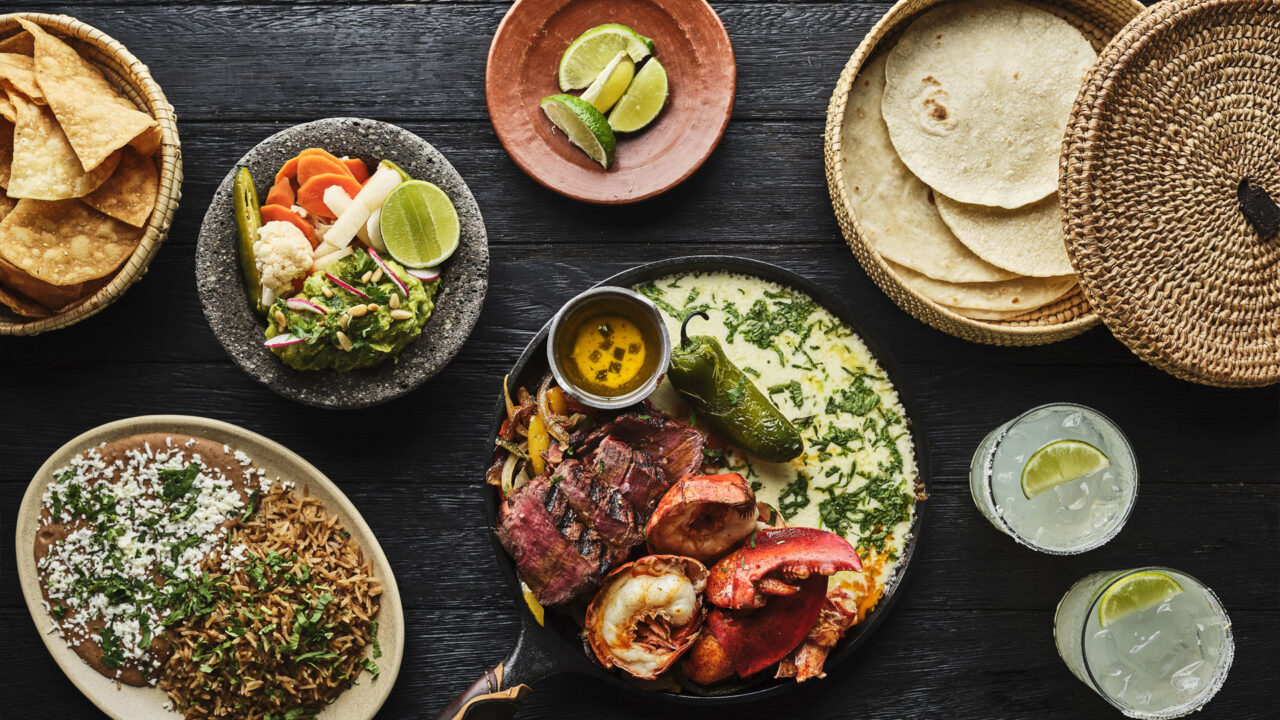 Colorful Mexican spread with tacos, chips, dips, and margaritas