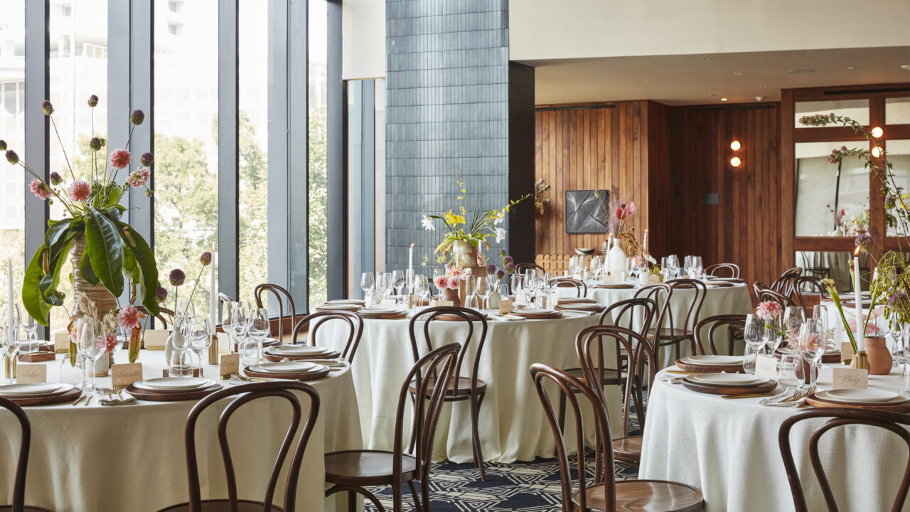 Elegant dining area with round tables, wooden chairs, and large windows.