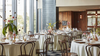 Elegant dining area with round tables, wooden chairs, and large windows.