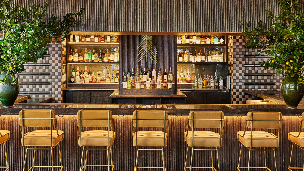 Chairs are neatly arranged in front of the bar counter, with wine bottles displayed on the showcase.