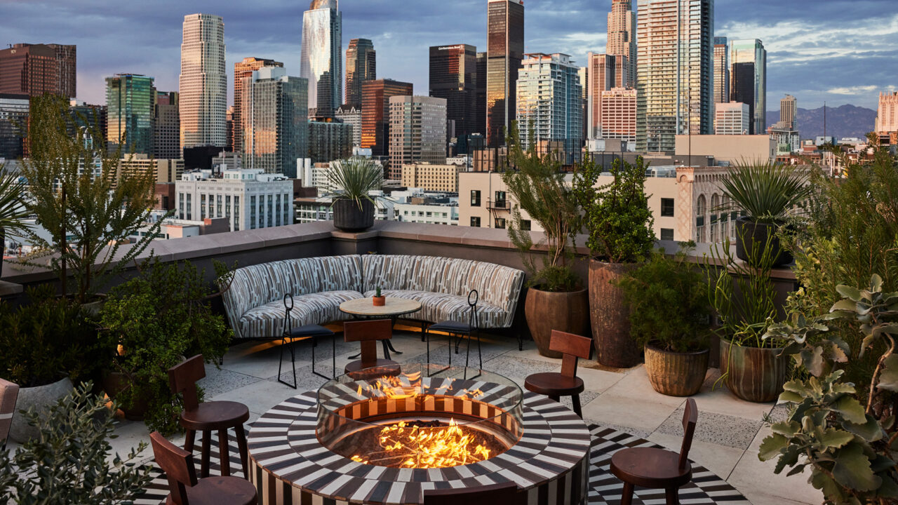 Rooftop lounge with fire pit seating and panoramic downtown Los Angeles skyline views