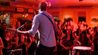 Live music performance with guitarist playing to a crowd in a vibrant indoor venue