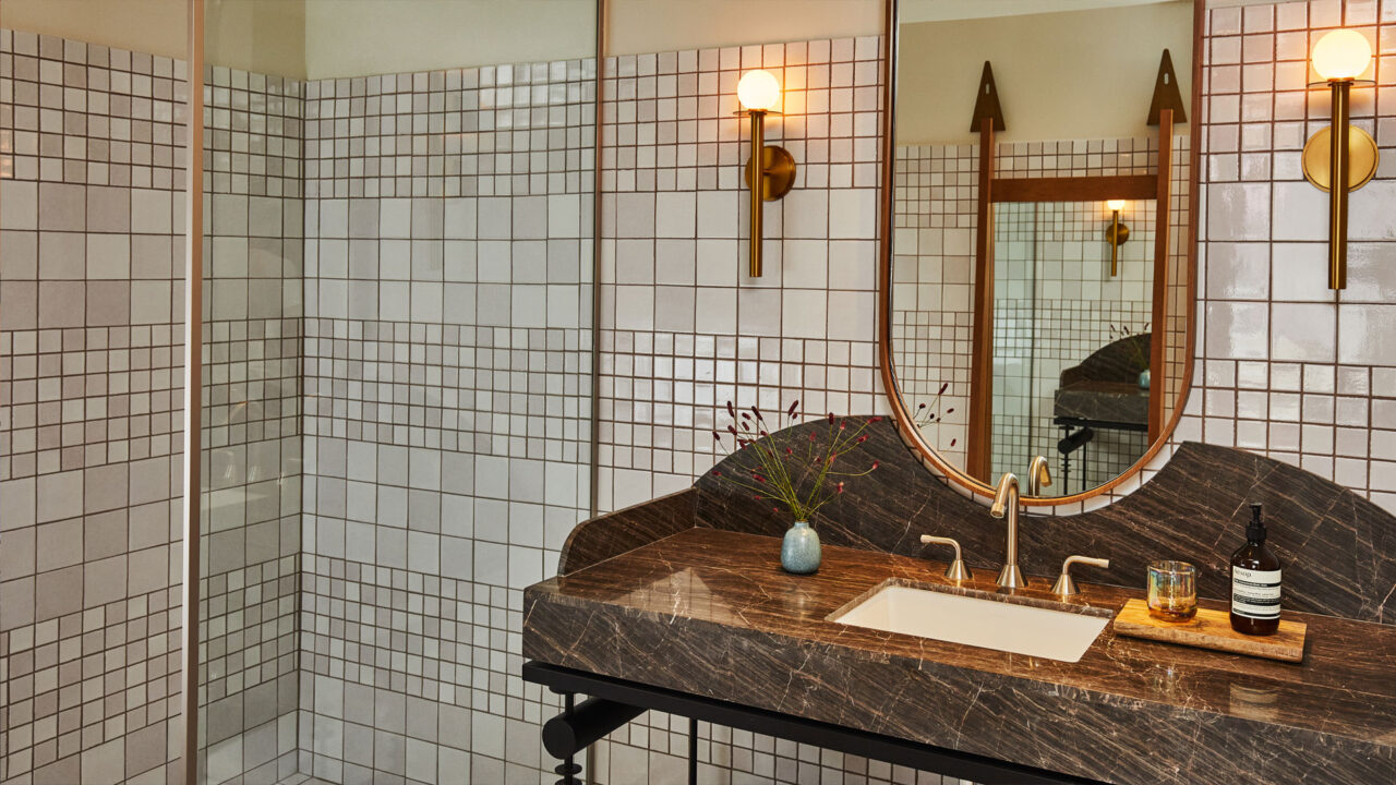 Modern tiled bathroom with marble vanity, brass fixtures, and contemporary design details