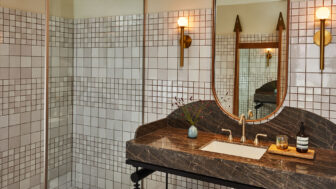 Modern tiled bathroom with marble vanity, brass fixtures, and contemporary design details