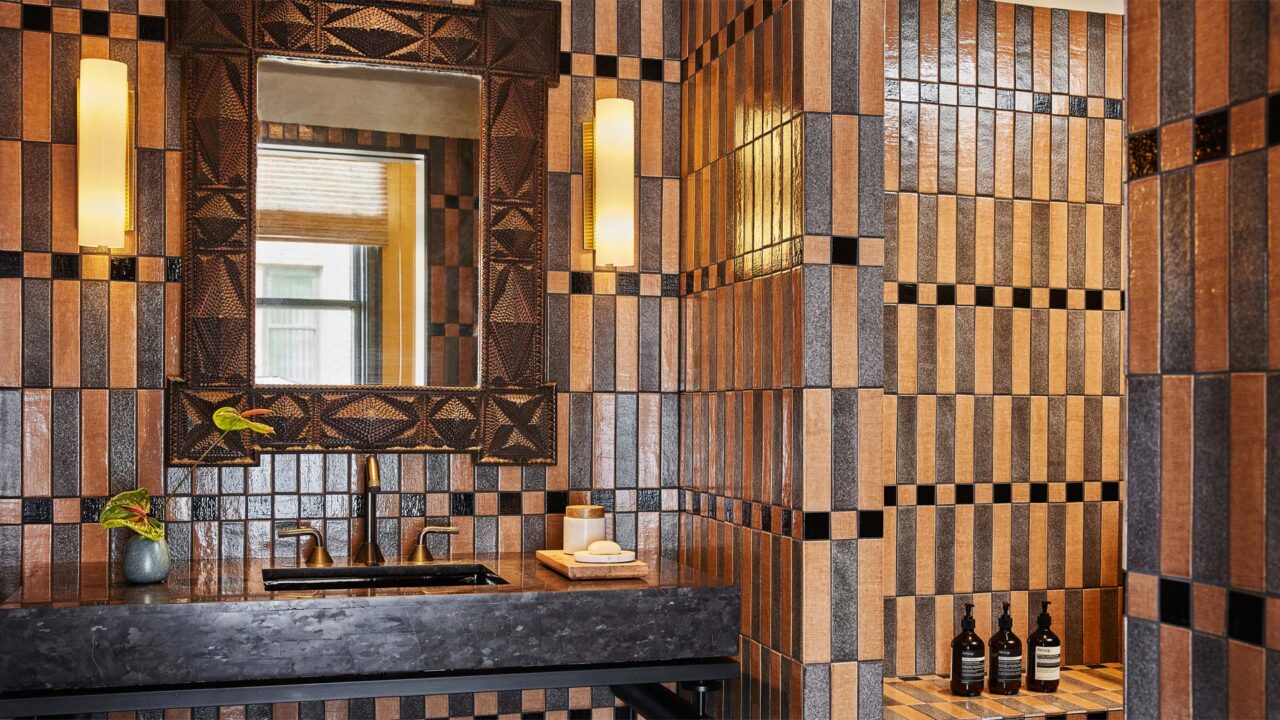 Luxury bathroom with geometric tiled walls, designer mirror, and modern stone vanity