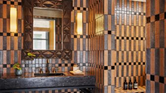 Luxury bathroom with geometric tiled walls, designer mirror, and modern stone vanity