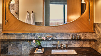 Modern bathroom vanity with marble backsplash, wooden mirror frame, and sink with elegant fixtures