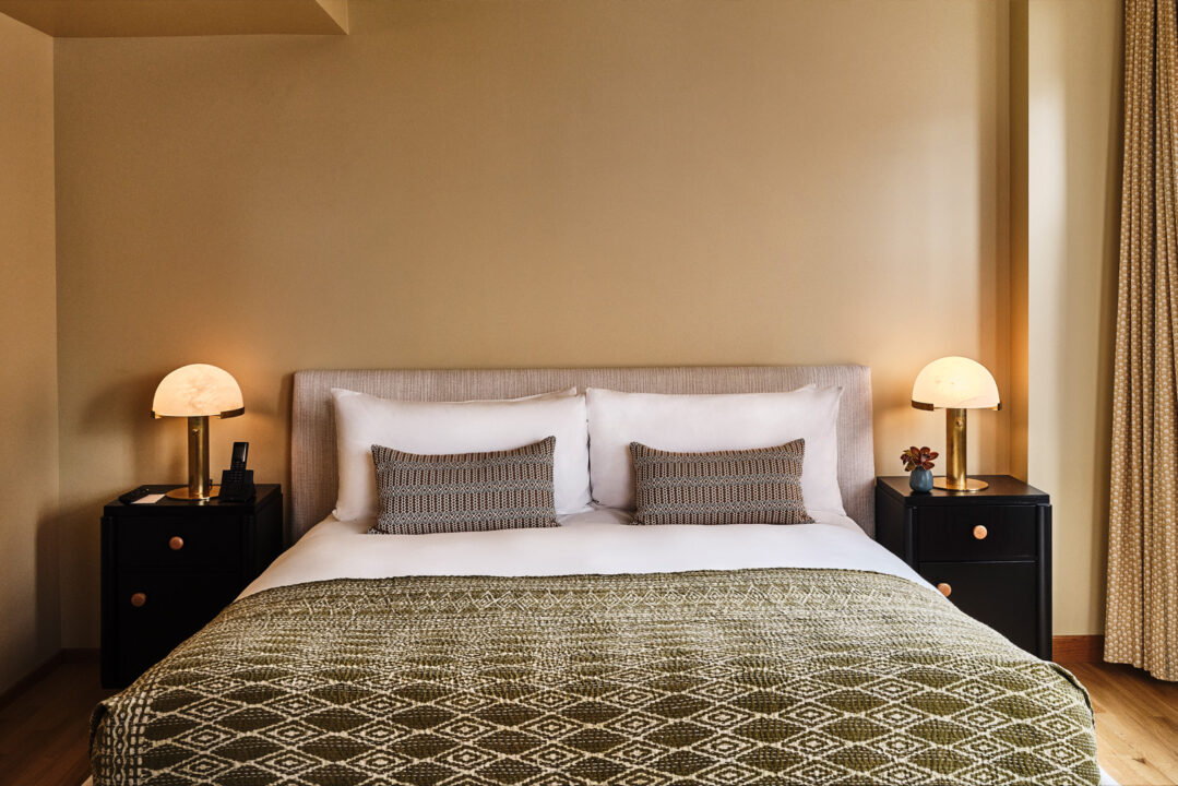 Minimalist king bedroom with soft lighting, patterned bedding, and modern bedside decor