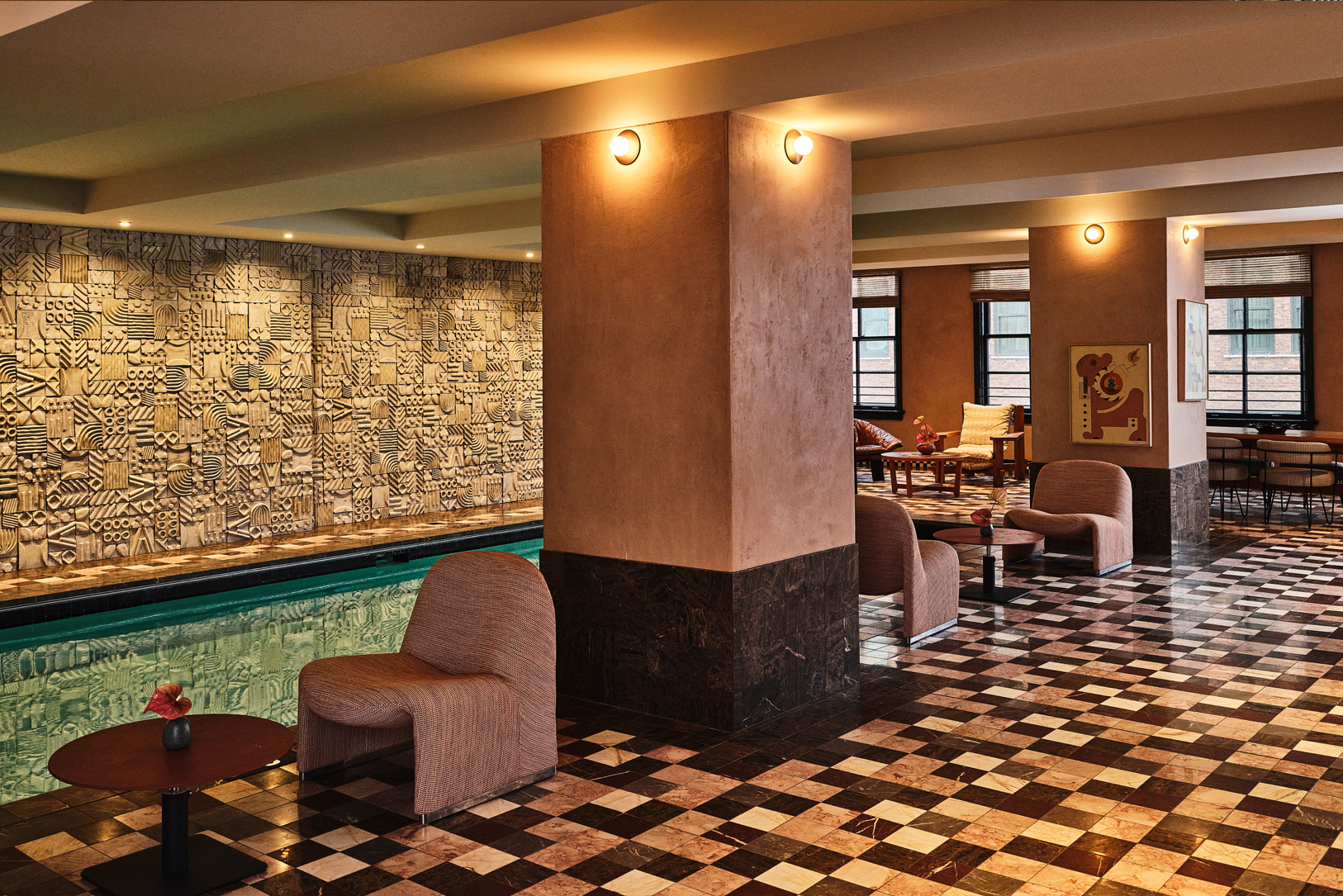 Indoor pool area with modern lounge chairs and tiled flooring.