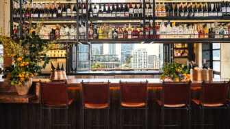 Chairs are placed near the bar counter, with wine bottles neatly displayed in the showcase.