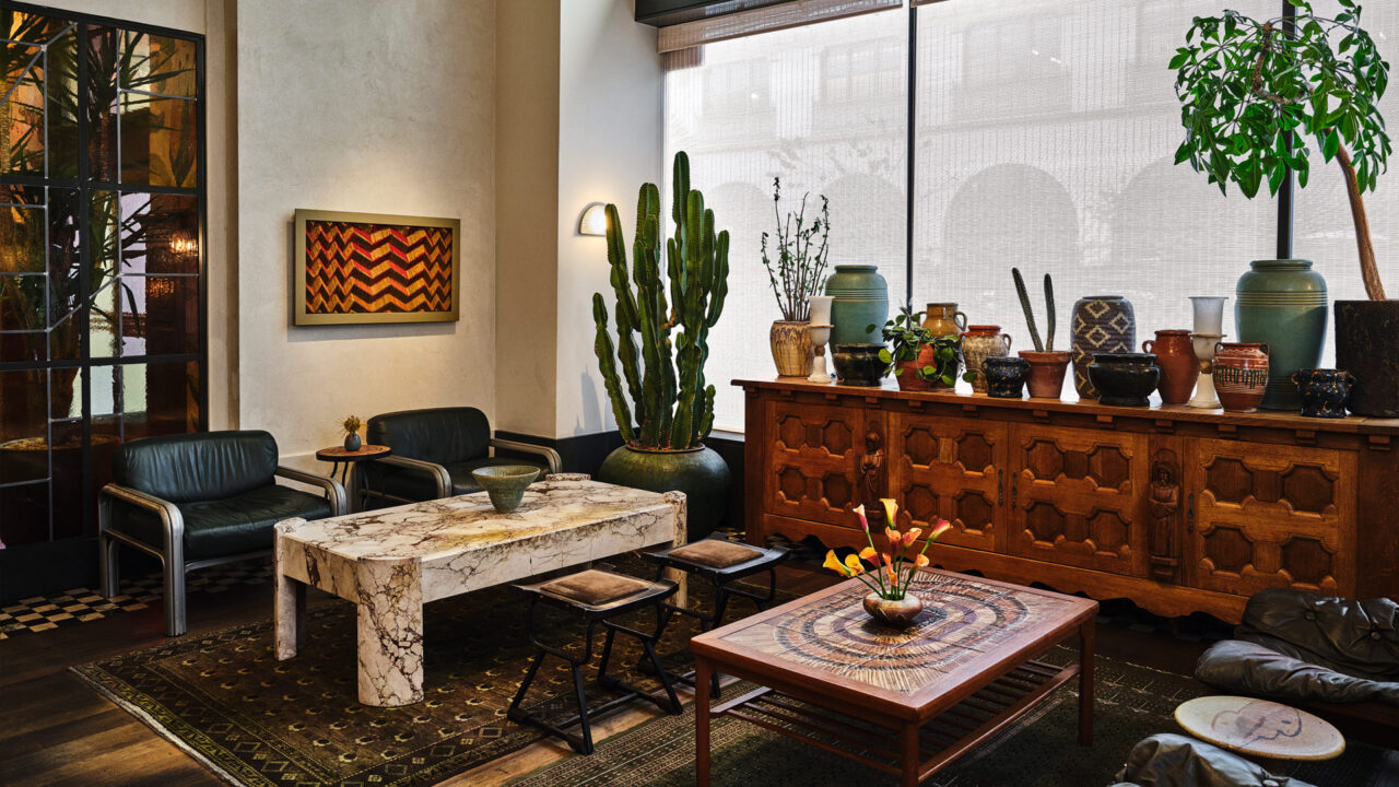 Two uniquely designed tables are accompanied by chairs, arranged near long cabinets displaying decorative vases.