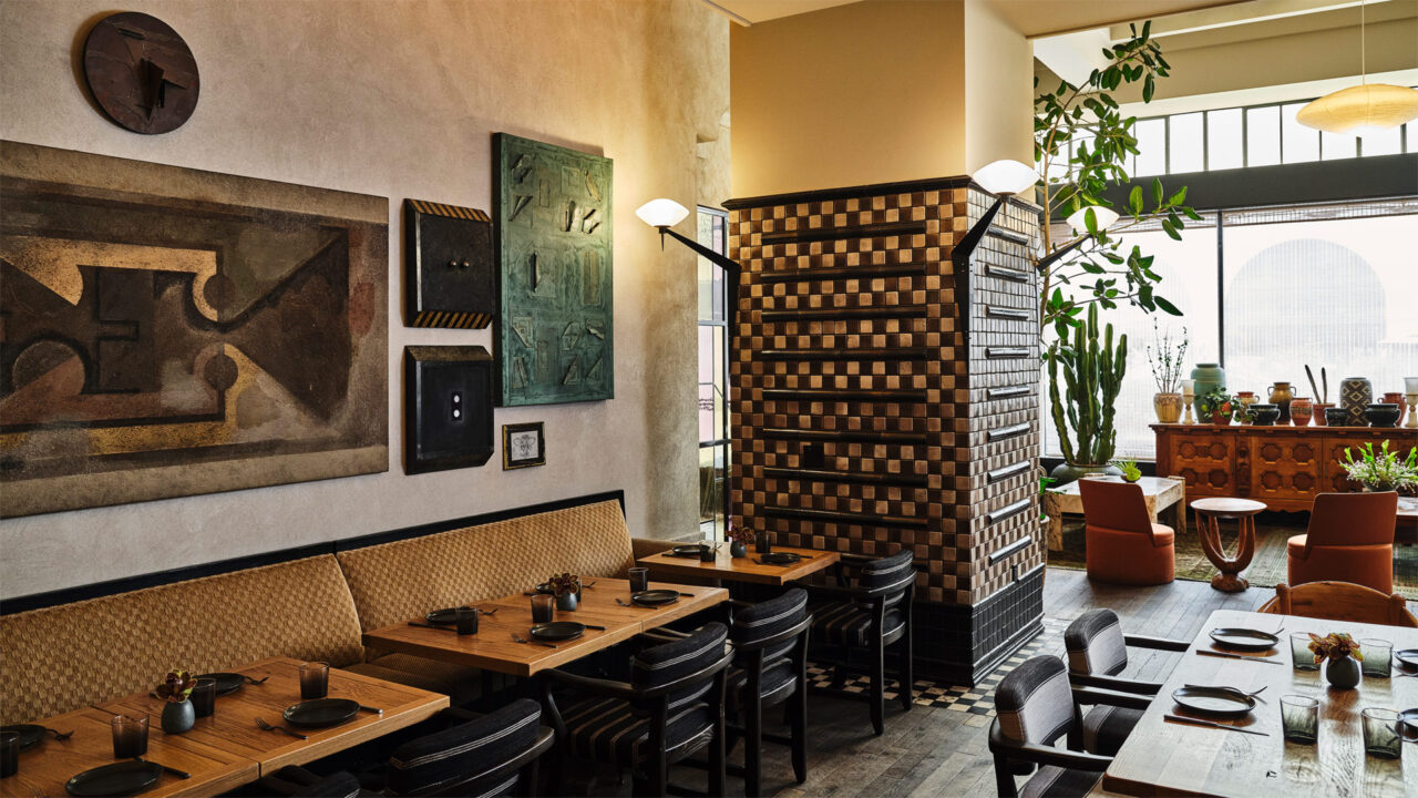 Numerous dining tables are accompanied by chairs, with portraits adorning the wall.