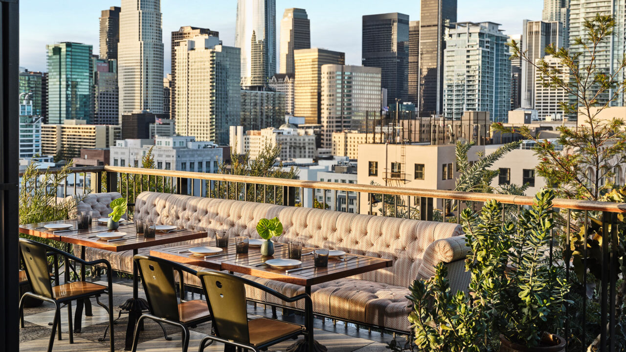 Rooftop terrace dining with panoramic city skyline views.