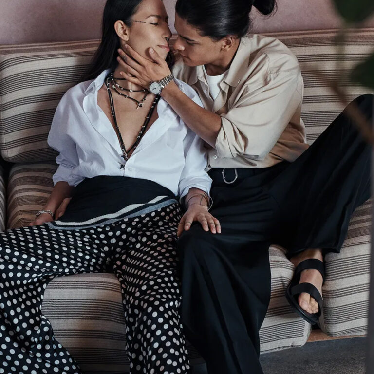 Two people sitting close together on a striped sofa, sharing an intimate moment in a cozy indoor setting