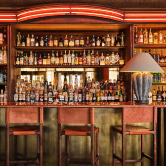 Stylish bar with leather stools, glowing red accents, and a curated wall of spirits