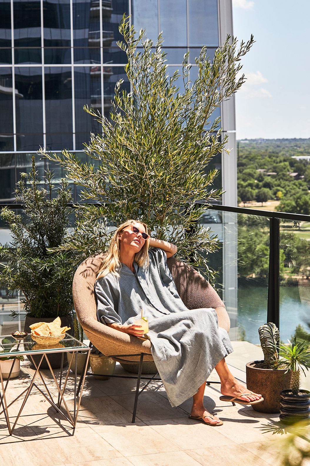 A girl enjoys a sunbath while sitting on her balcony.